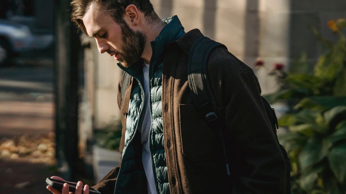 Man checking his phone while walking in a busy street