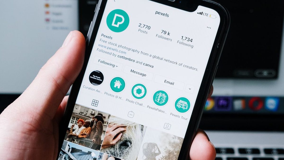 Hand holding a phone with social media reaction icons